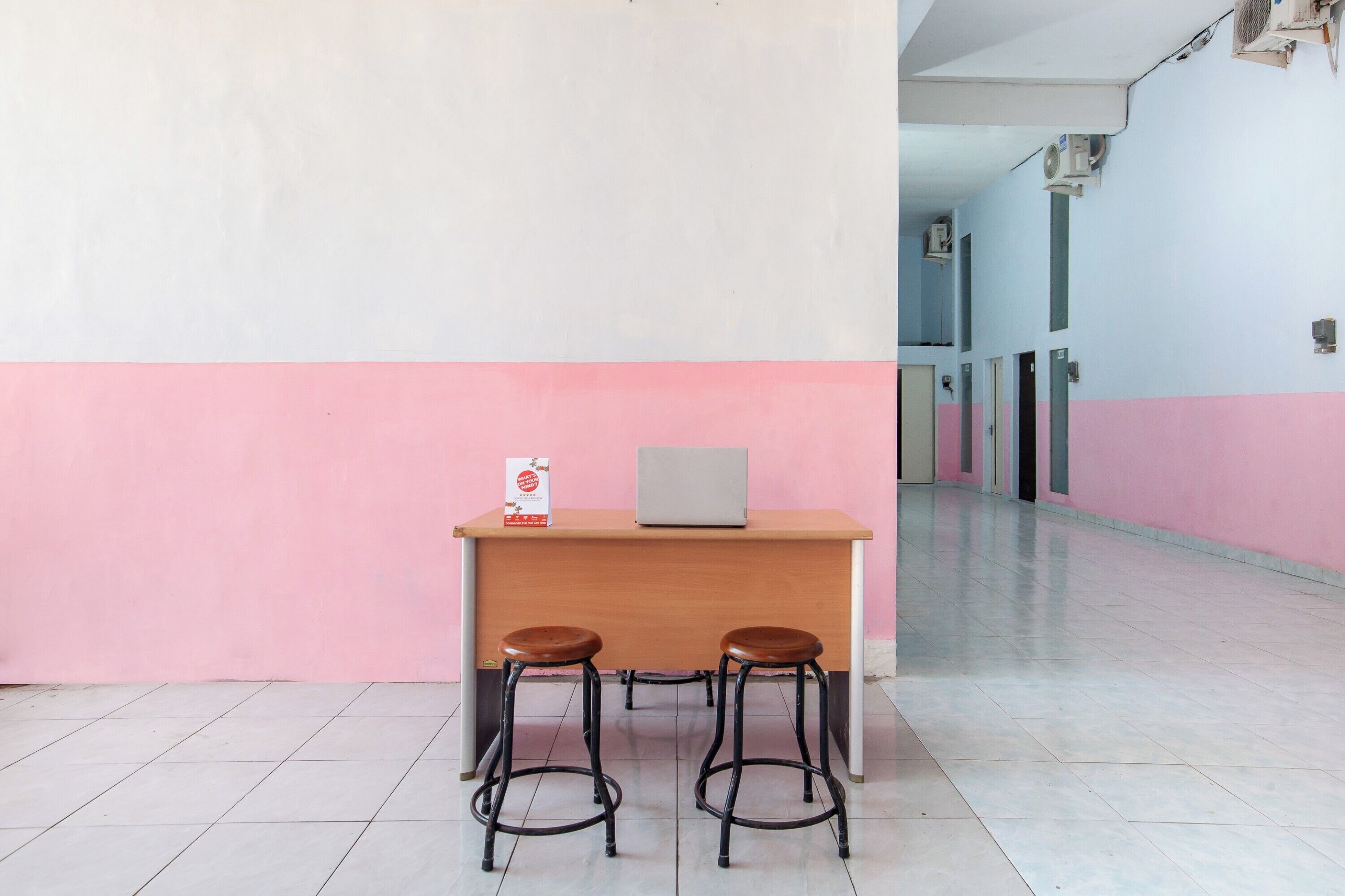 A reception desk with a laptop, two stools, and a sign.