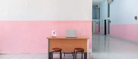 A reception desk with a laptop, two stools, and a sign.