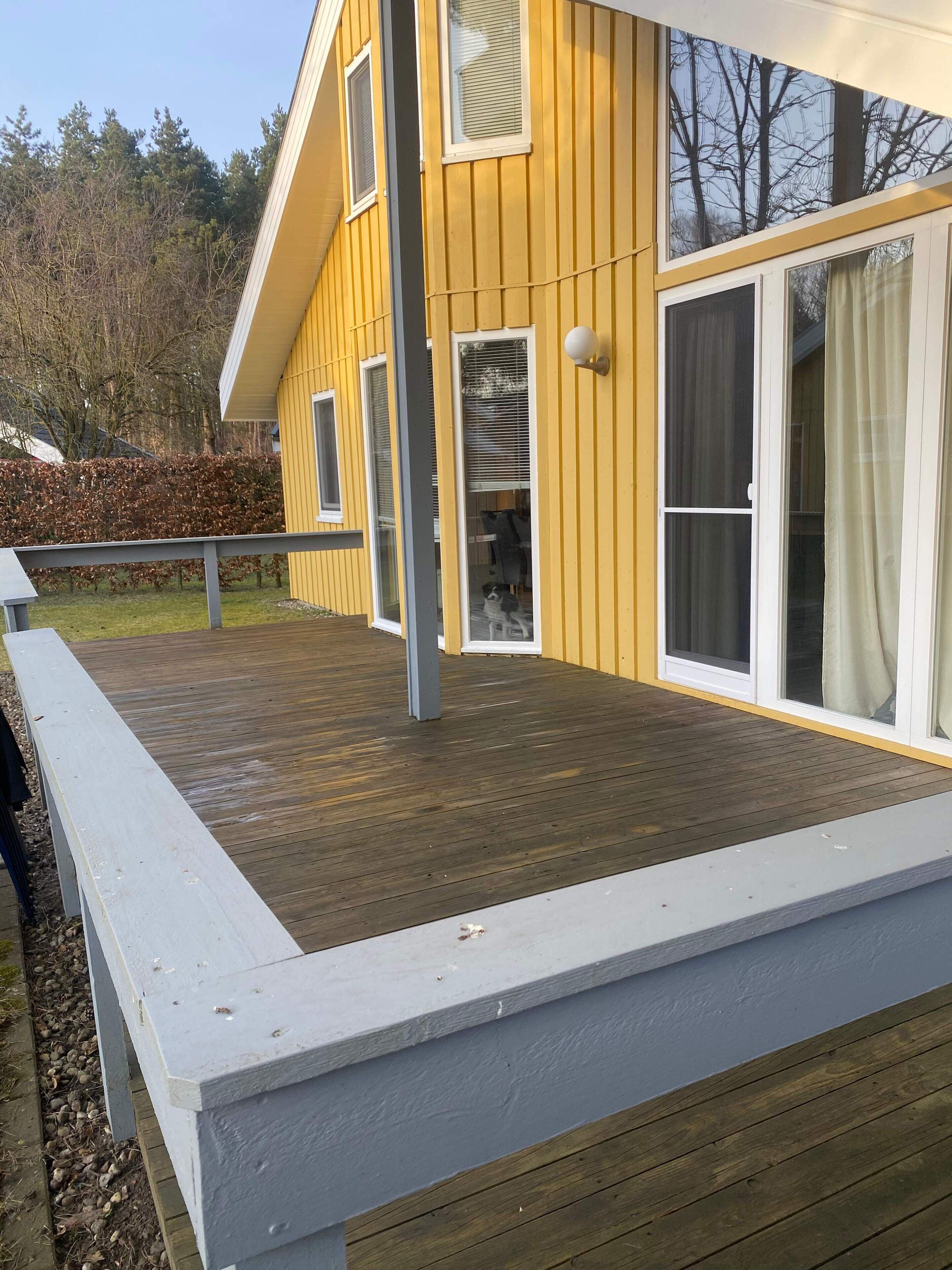 A yellow house with a wooden deck and a white railing.