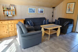 Una sala de estar con un sofá, una mesa de centro, un aparador de madera y una estantería.