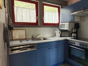 Cocina compacta equipada con lavaplatos, estufa, microondas y cafetera.