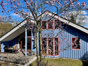A blue building with red-framed windows and a covered patio area with outdoor seating.