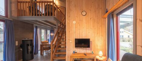 Ein Holzinnenraum mit Fernseher, Sofa und Treppe.