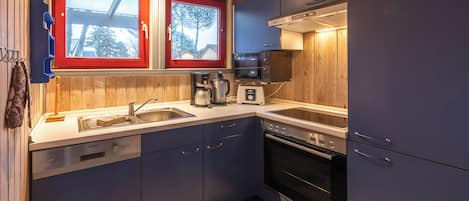 Una cocina moderna con lavavajillas, horno, microondas y una ventana con marco rojo.