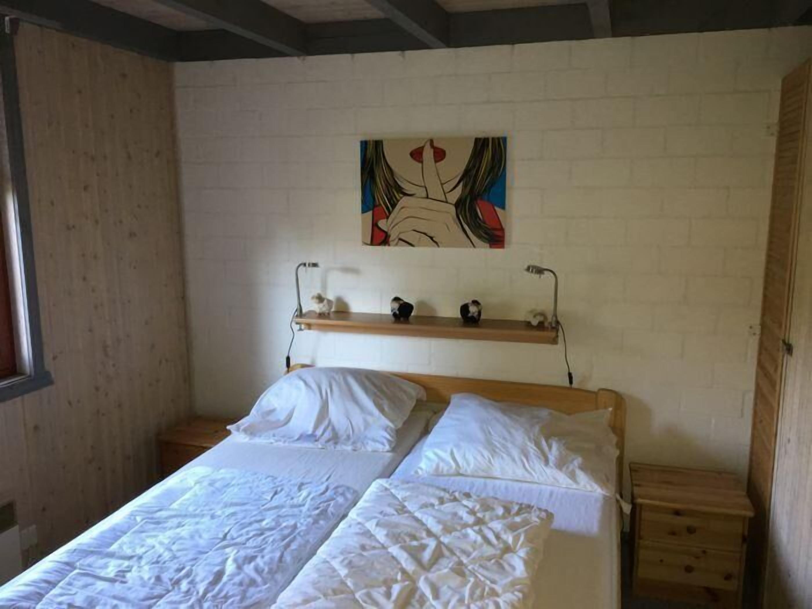 Ein Schlafzimmer mit einem Bett, einem Nachttisch, einer Wandregal mit Dekoration und einem Fenster.