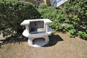 Een stenen constructie in een tuin met weelderige begroeiing en een gebouw op de achtergrond.