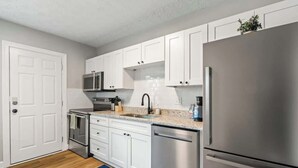Una cocina moderna con armarios blancos, electrodomésticos de acero inoxidable y un tapete azul.