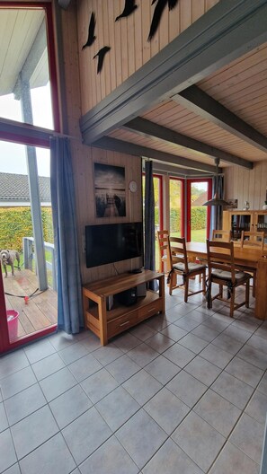 A spacious living area with a television, wooden furniture, and a view of the outdoors.