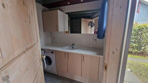 Un baño pequeño con lavadora, lavamanos y armarios de madera.