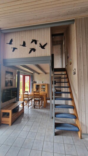 Un interior de madera con escalera, comedor y televisor de pantalla plana.