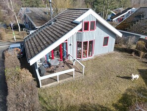 Una casa con techo inclinado, un porche con sillas y una pequeña terraza.