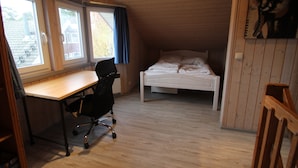 Une pièce avec un bureau en bois, un lit et une fenêtre avec des rideaux.