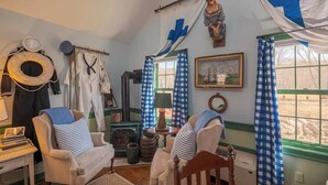 Een gezellige kamer met een open haard, een schommelstoel en een raam met blauwe gordijnen.
