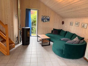 Una habitación acogedora con detalles de madera, un sofá verde, una mesa de madera y un calentador negro.