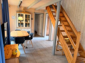 Un interior de madera con comedor, una alacena con puertas de cristal y una escalera.