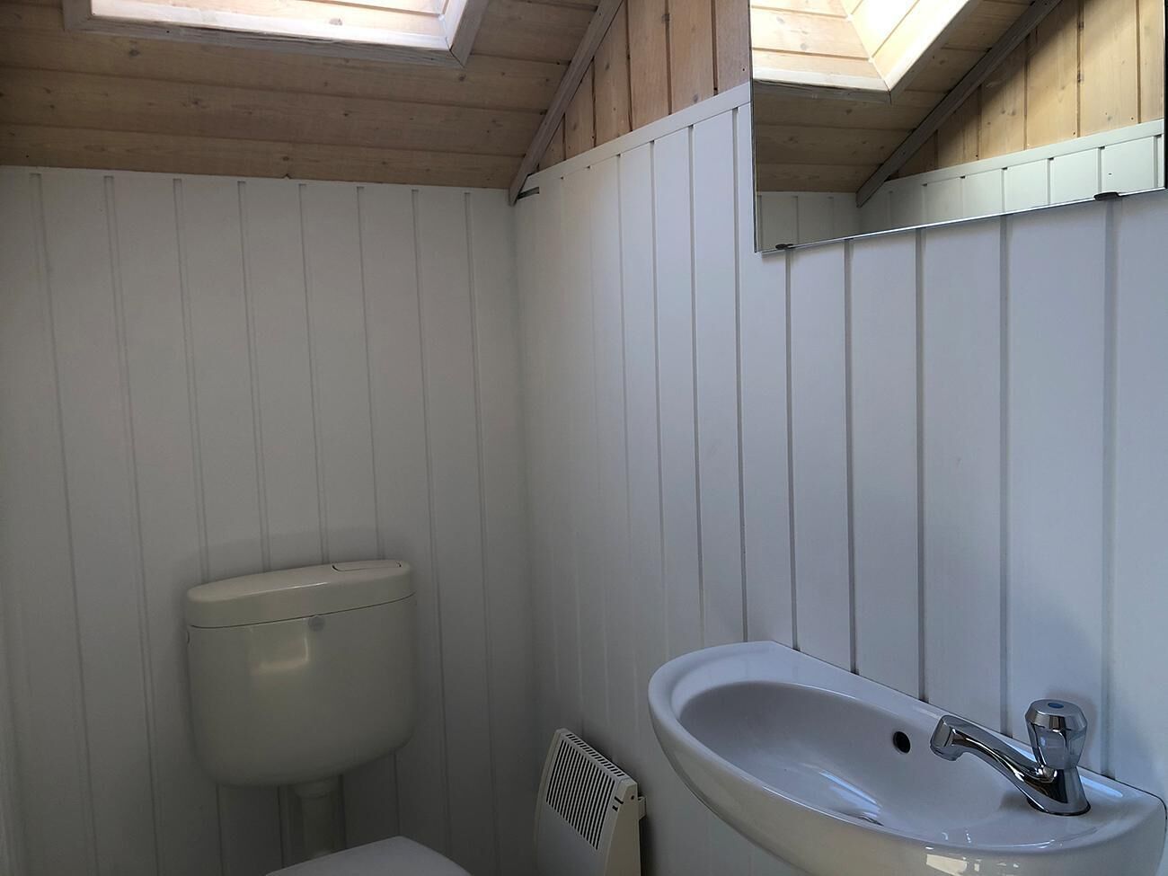 Un baño pequeño con inodoro, lavamanos y tragaluz.