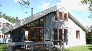 Ein zweistöckiges Haus mit einem geneigten Dach, großen Fenstern und einer Veranda.
