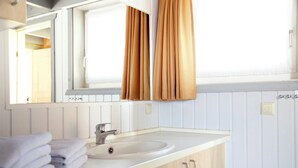 Ein Badezimmer mit Waschbecken, Spiegel und beigen Vorhängen.