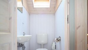 Ein schmales, einzelnes Badezimmer mit Dachfenster, Toilette und Waschbecken.