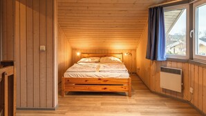 Puisilla paneeleilla verhoiltu huone, jossa on sänky, ikkuna, jossa on verhot, ja patteri.