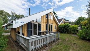 Moderni, kaksikerroksinen talo, jossa on puinen julkisivu, parveke ja valkoinen aita.