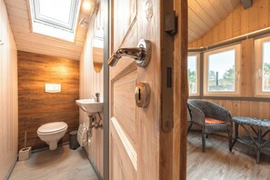 Ein Holzinnenraum mit Toilette, Waschbecken und Korbstuhl.