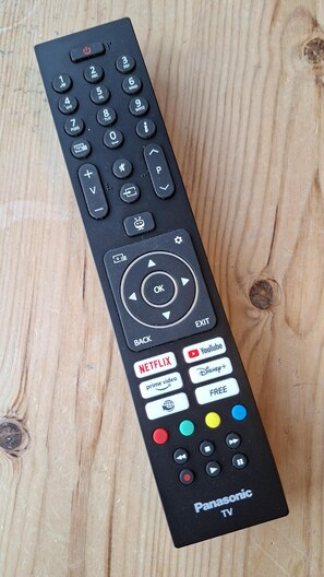 Controlo remoto preto da Panasonic com teclado numérico, painel de direções e botões de função incluindo Netflix, YouTube e Prime Video.
