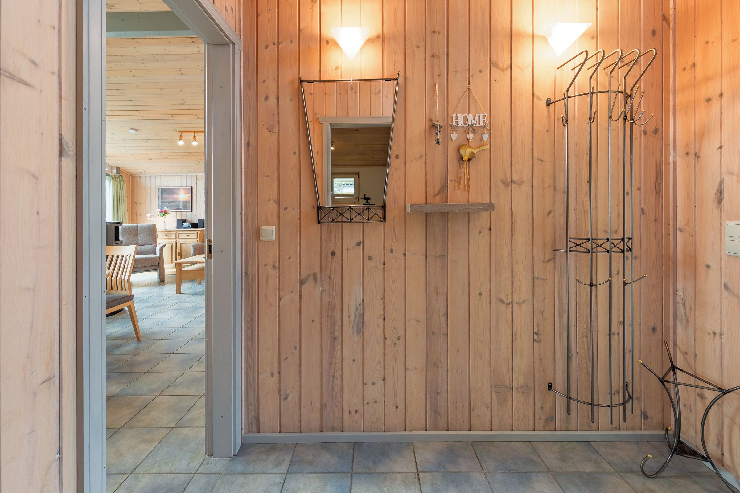 Un intérieur en bois agrémenté d’un miroir, d’un porte-manteau et d’une enseigne indiquant « MAISON ».