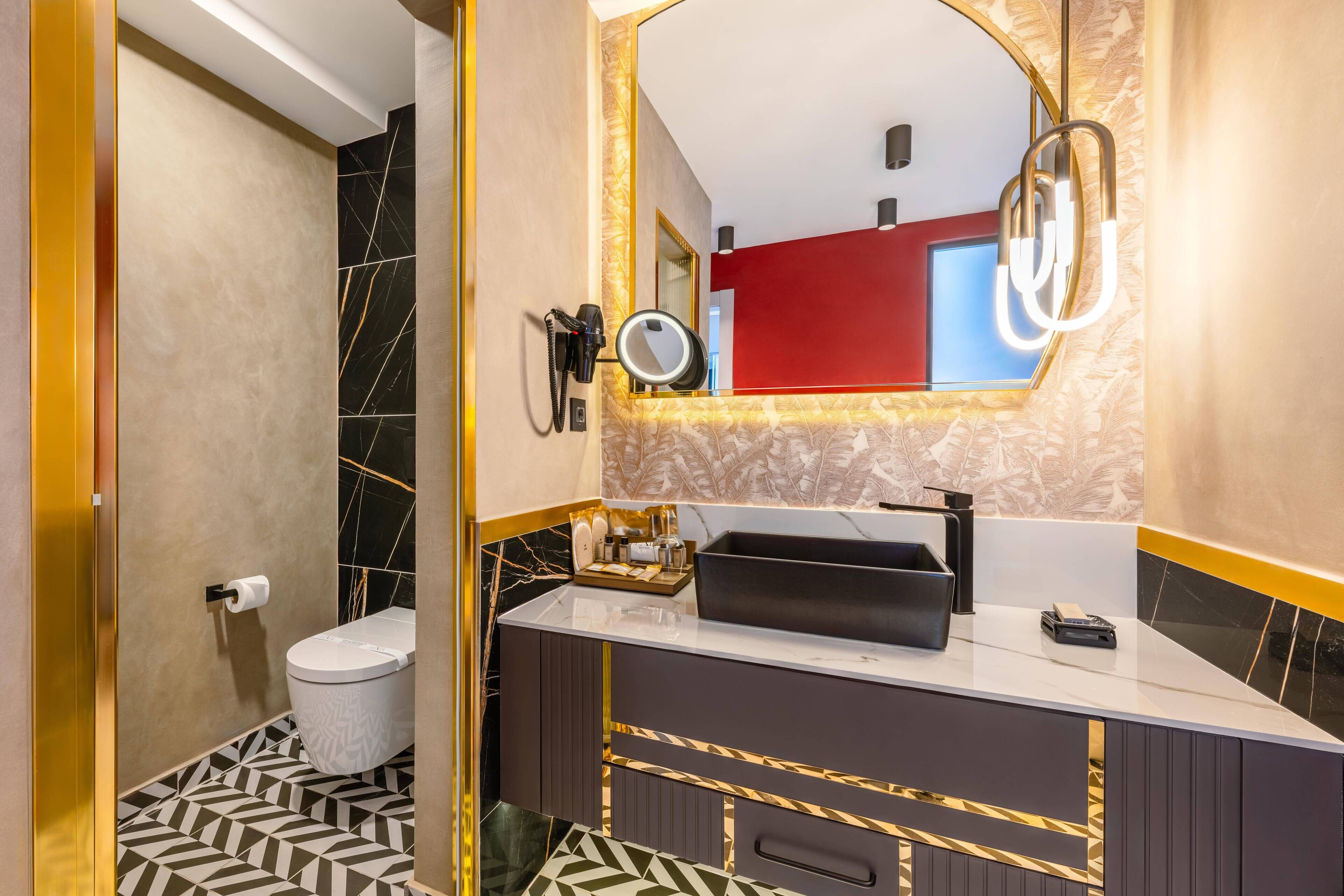 A modern bathroom with a marble vanity, a toilet, and a mirror with lights.