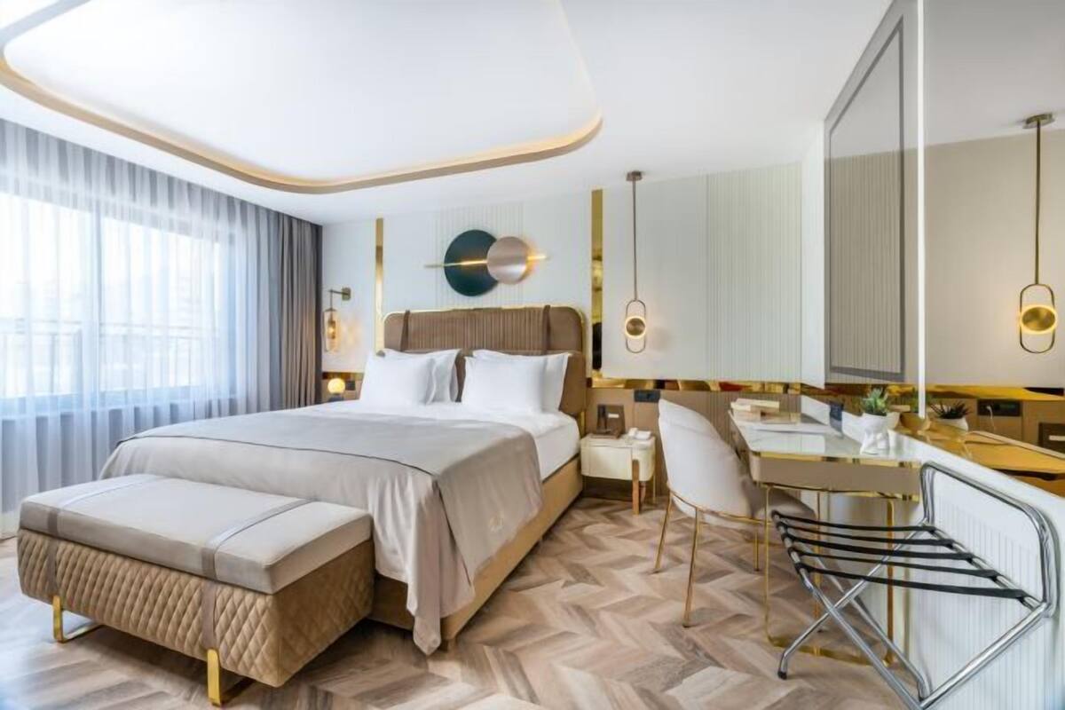 A modern hotel room with a large bed, a desk, and a chair.