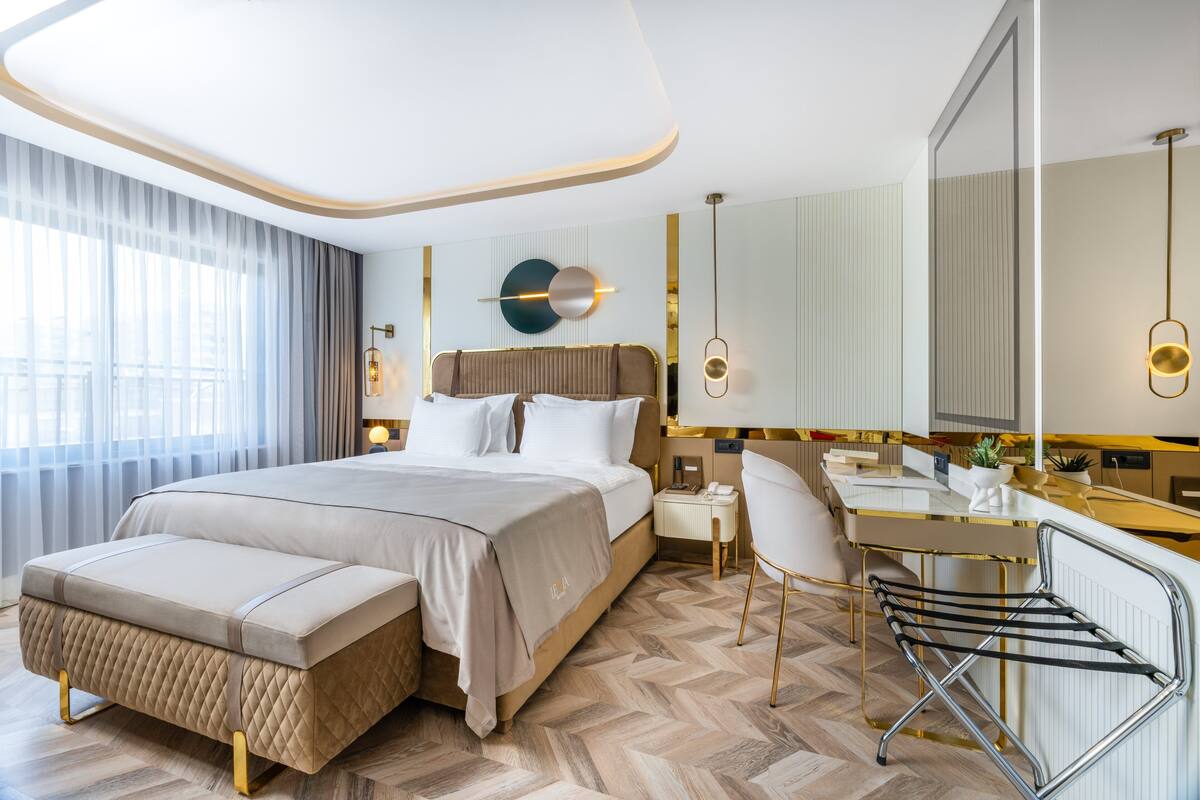 A modern hotel room with a large bed, a desk, and a chair.
