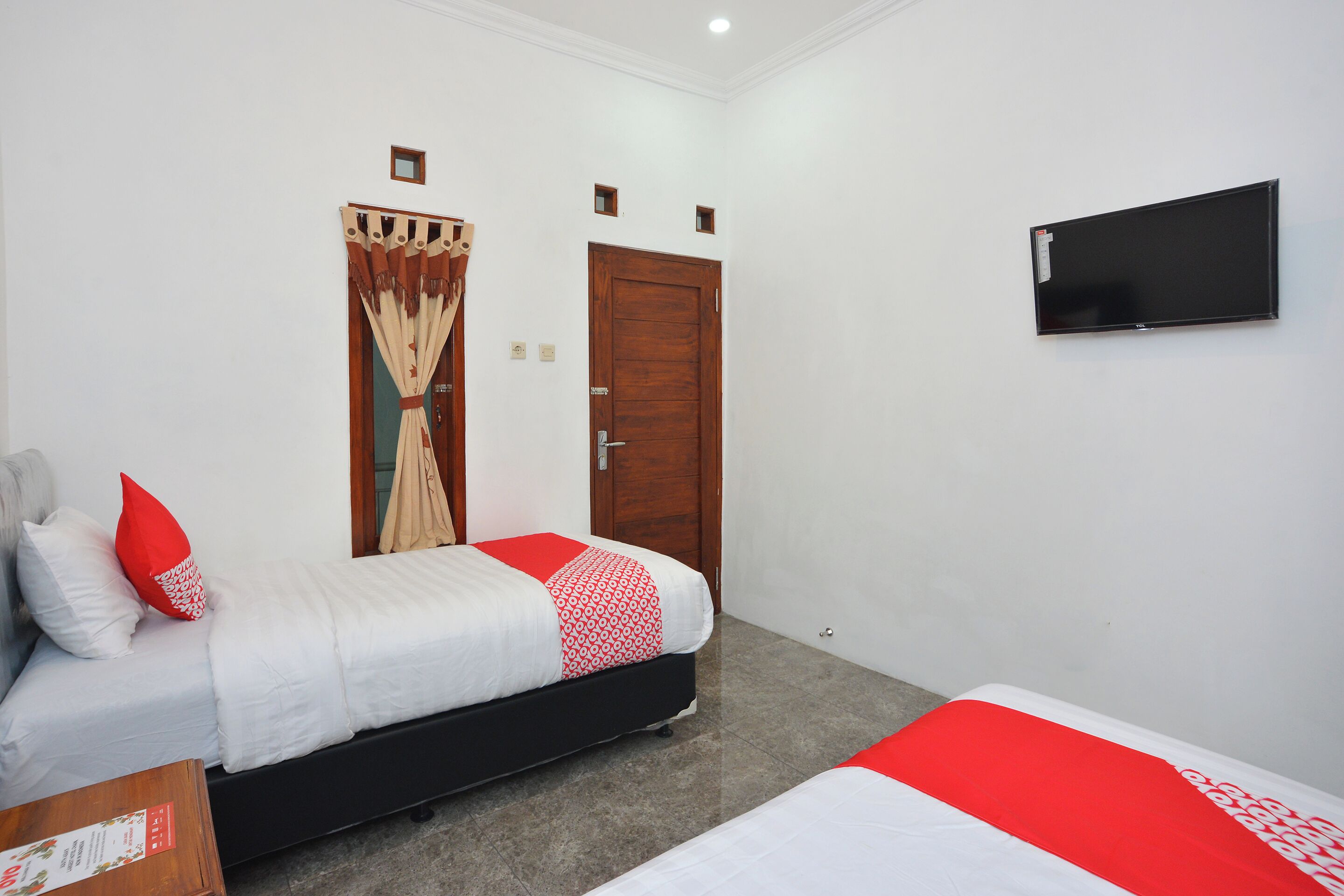 Una habitació d'hotel amb un llit, un televisor fixat a la paret i una porta.