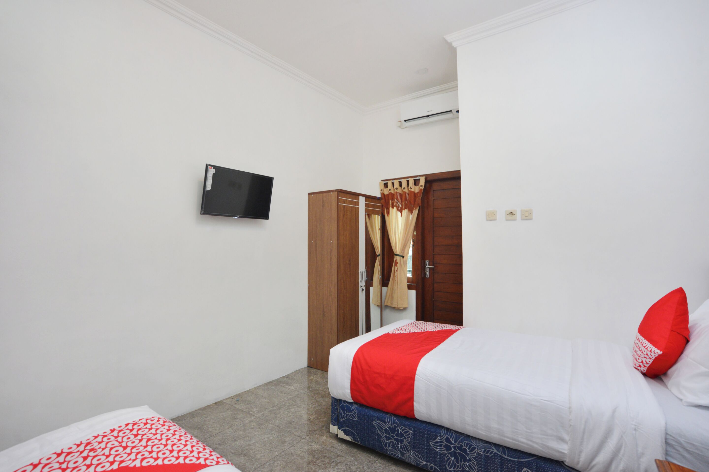 Ein Schlafzimmer mit einem Bett, einem an der Wand befestigten Fernseher und einem Kleiderschrank.