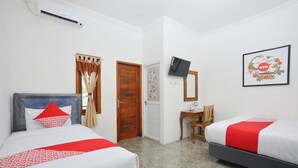 A hotel room with two beds, a desk, a television, and a framed picture on the wall. - OYO 634 Elga Sastro Inn Syariah (Yogyakarta)