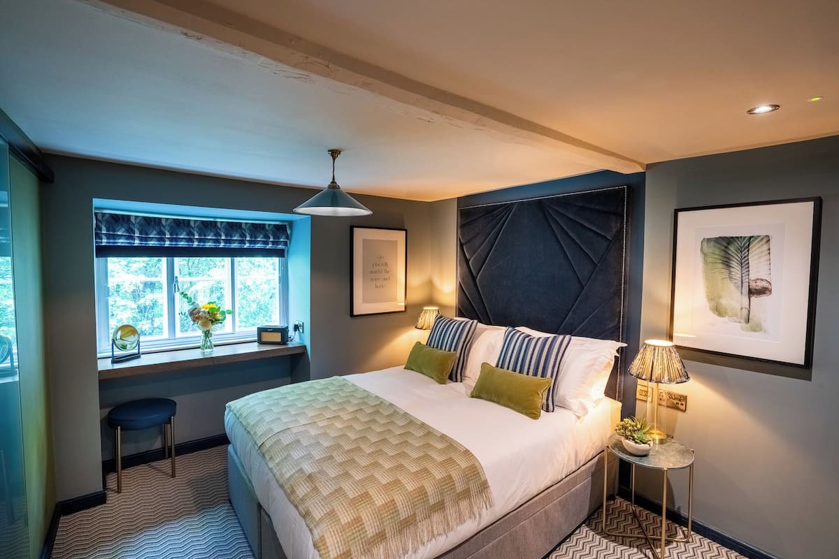 A bedroom with a large bed, a window with a view, a desk, and a chair.