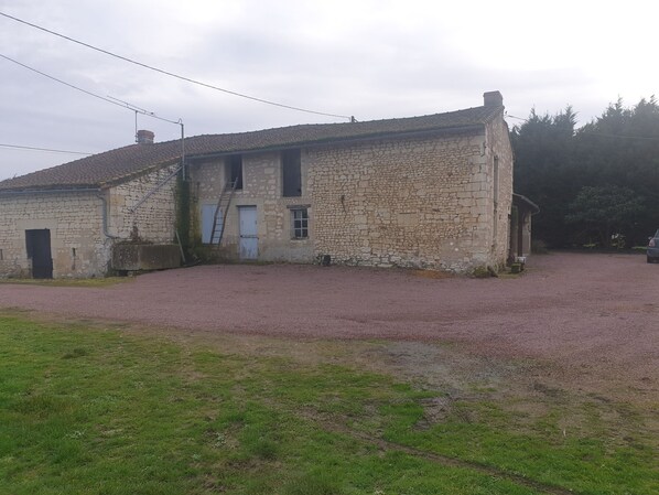 Un edificio de piedra con un camino de grava y un área verde al frente.