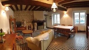 Una sala de estar acogedora con chimenea de piedra, muebles de madera y piso a cuadros.