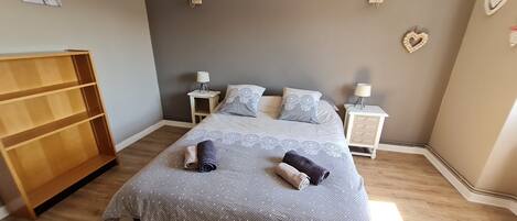A bedroom with a bed, two bedside tables, a wooden wardrobe, and decorative wall art.