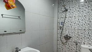 A bathroom with a white sink, a mirror, a shower with a tiled wall, and a toilet. - Hotel O Cozy Residence Syariah (Malang)