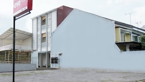 A building with a white facade, a red sign, and a balcony. - Hotel O Cozy Residence Syariah (Malang)