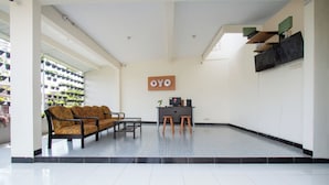 A reception area with a sofa, chairs, a small table, and a sign that reads "OYO". - Hotel O Cozy Residence Syariah (Malang)