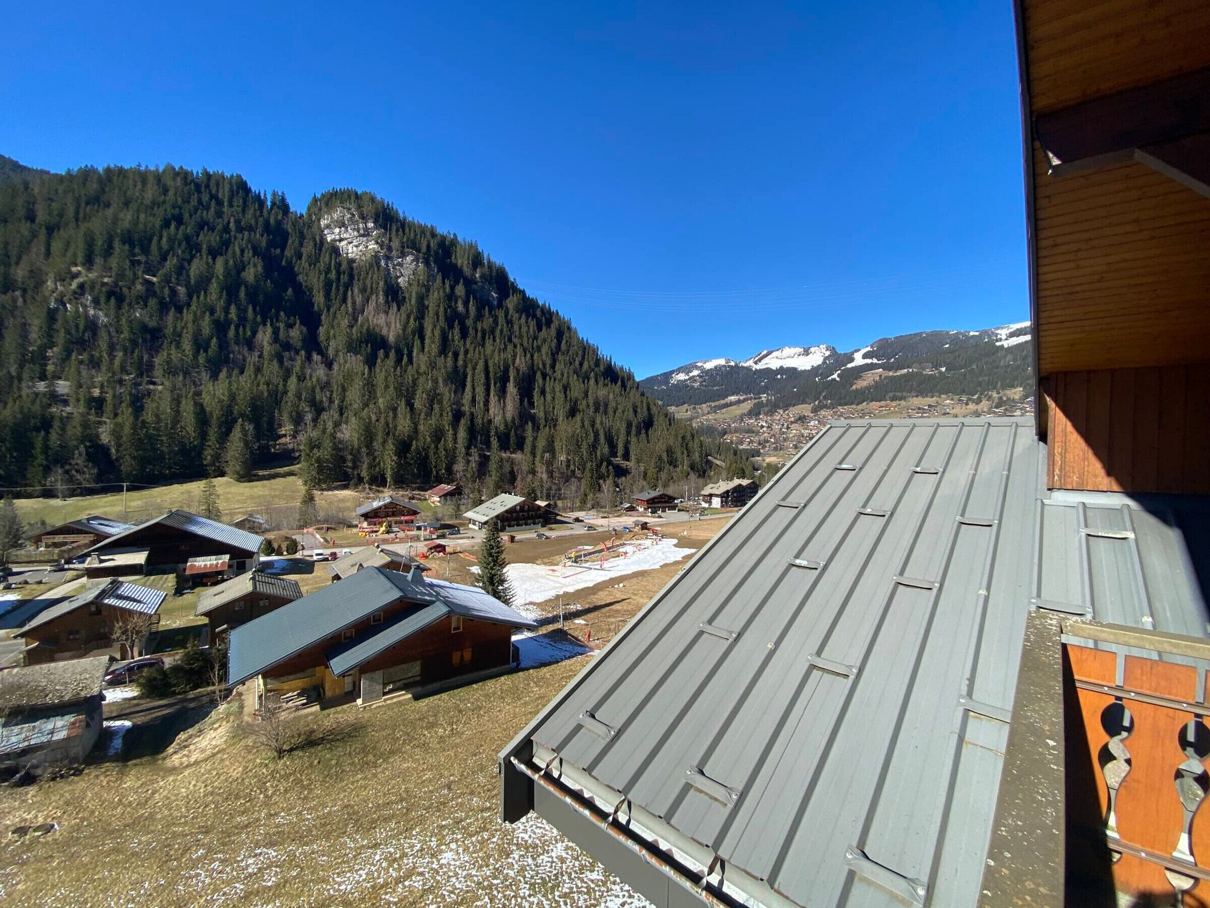 A mountain village with traditional wooden buildings and a view of snow-capped peaks.