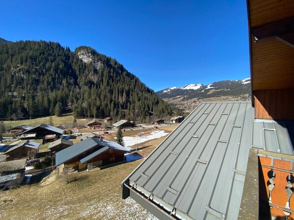 Un village de montagne aux bâtiments traditionnels en bois, offrant une vue sur des sommets enneigés.