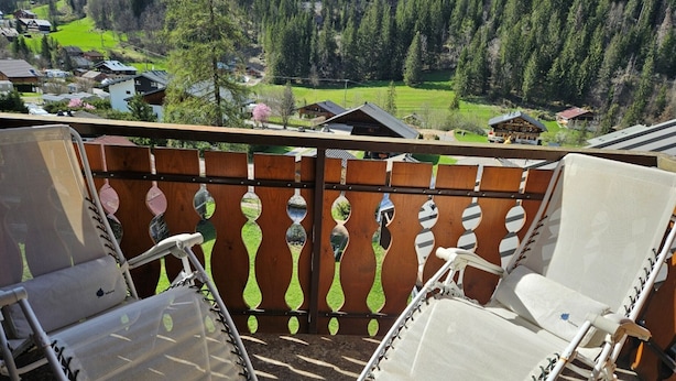 A balcony with two white chairs and a wooden fence with decorative elements. - Charming duplex with balcony, near ski and shuttle, parking, WIFI (Châtel)