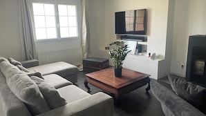 En moderne stue med en sofa, et sofabord og et fjernsyn hængt på væggen.