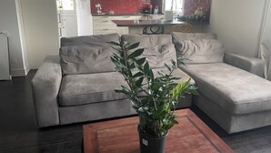 En stue med en grå sofa, et træbord og en potteplante.