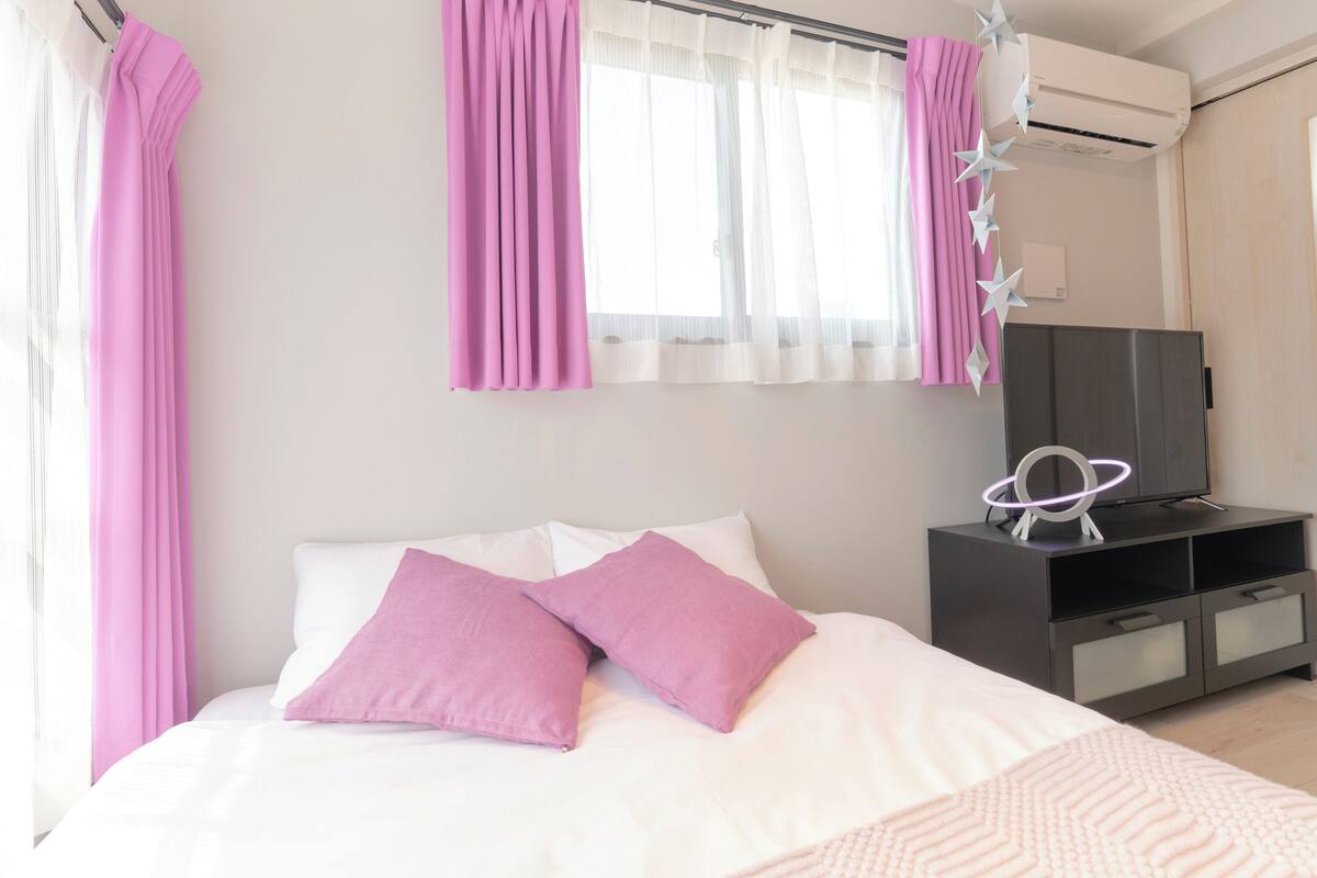 Un dormitorio con cama, almohadas, televisor y armario.