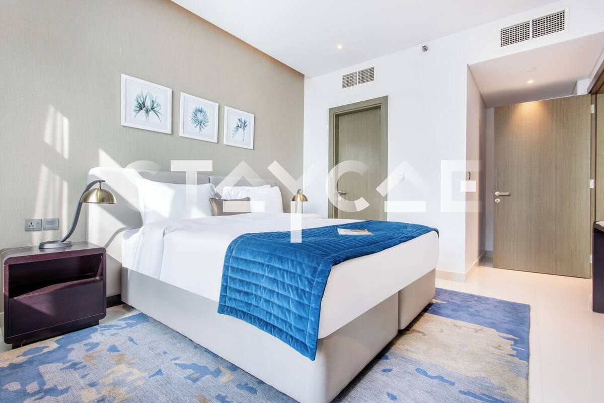 A modern bedroom with a bed, bedside table, lamp, and artwork on the wall.
