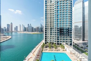 A high-rise hotel with a rooftop pool overlooking a body of water and a city skyline. - Staycae Holiday Homes Prive (Dubai)