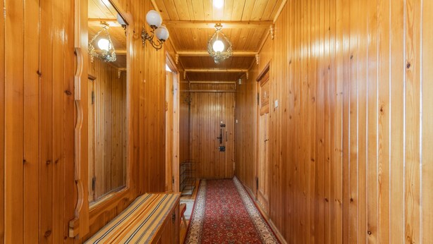 A wooden hallway with a bench, a patterned carpet, and a chandelier. - Sopocki Kredensik by Grand Apartments (Sopot)